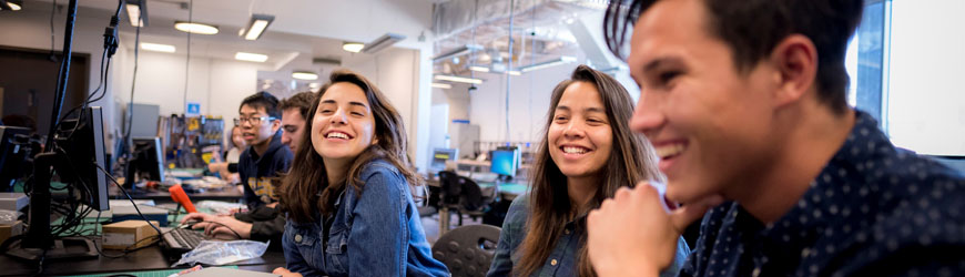 three students smiling in a computer lab