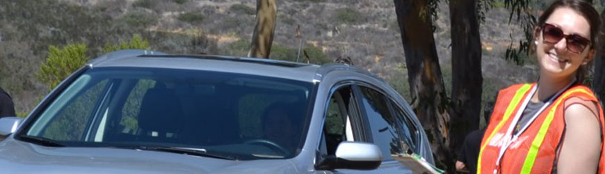 Student in orange vest next to a car