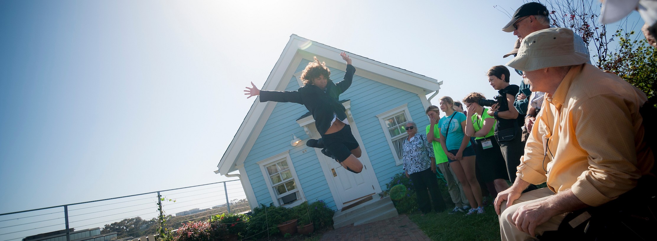 student jumping in front of Fallen star, a house in Warren College